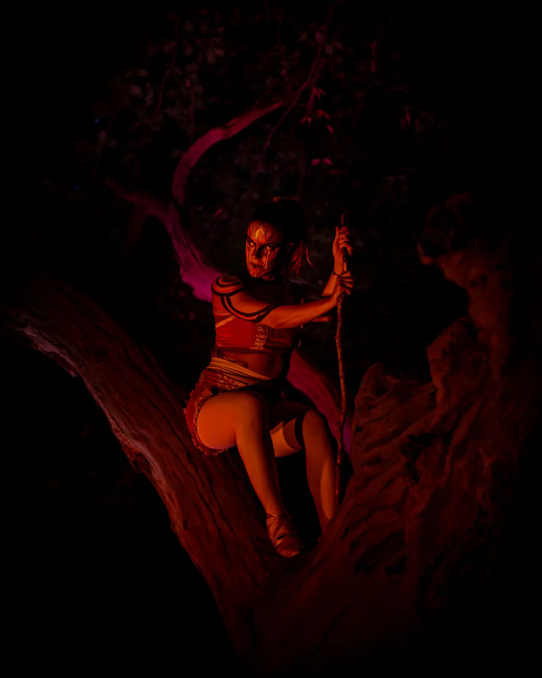 Rot beleuchtete Gestalt klettert mit einem Seil in einen alten Baum