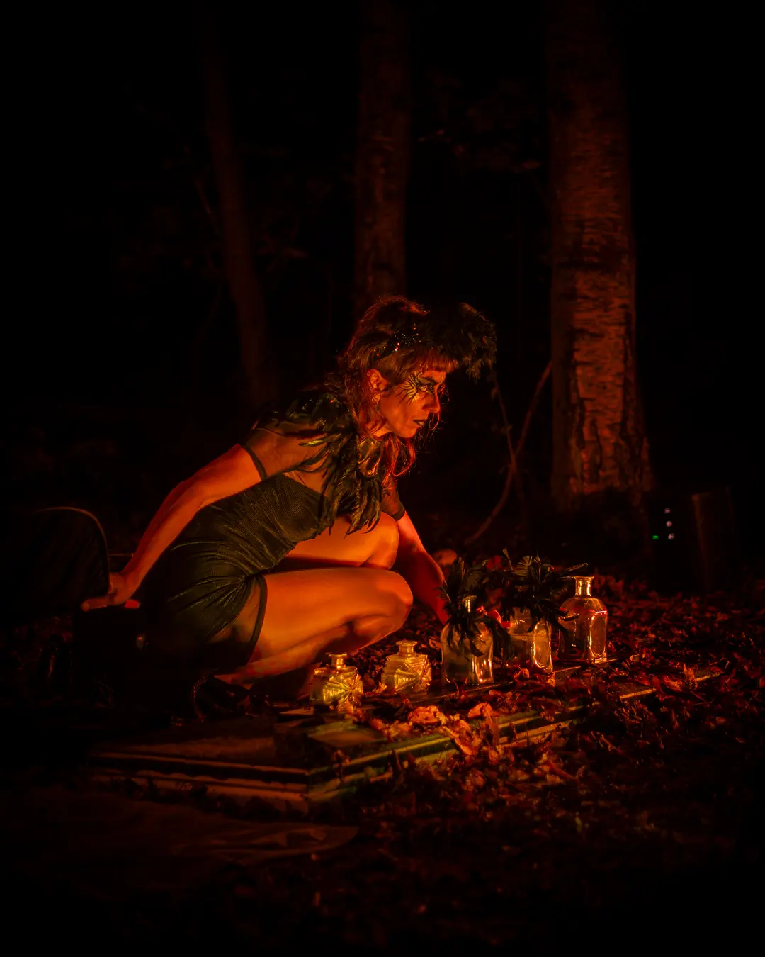 Gestalt kauert im orangefarbenen Licht vor leuchtenden Gläsern auf dem Waldboden