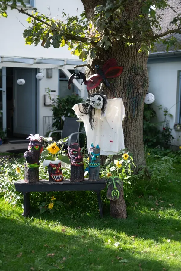 Geschmückter Vorgarten mit fantasievollen Figuren und Sonnenblumen
