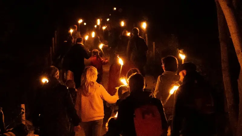 Fackelwanderung in Graal-Müritz: eine Gruppe mit brennenden Fackeln auf dem Weg durch die Dunkelheit