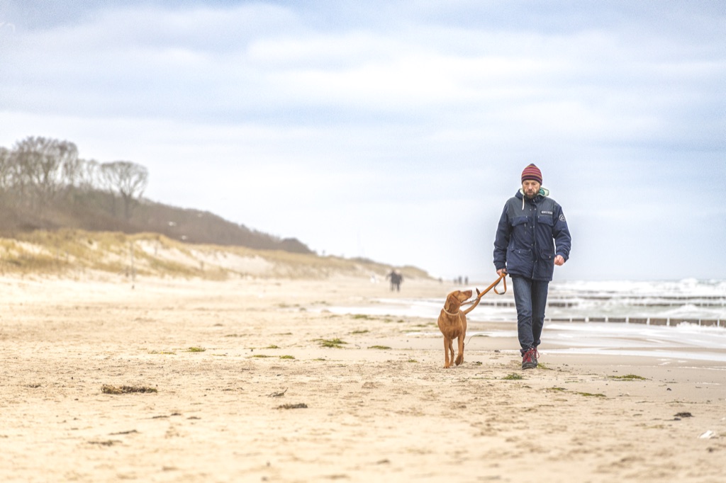 Spaziergang mit Hund an der Leine am Strand von Graal-Müritz