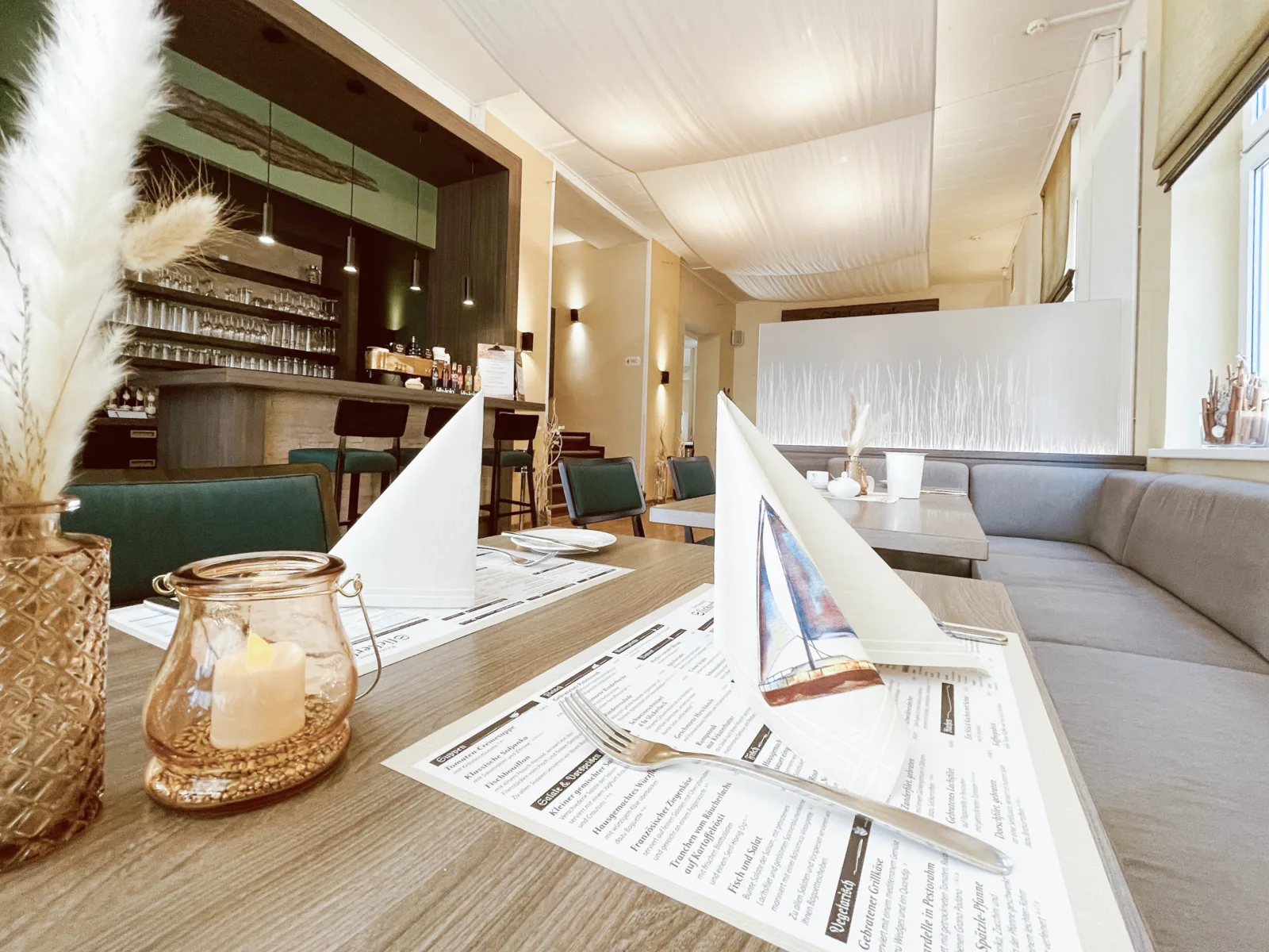 Gastraum des Restaurants Slickerbeck in Graal-Müritz – gedeckter Tisch mit Speisekarte und Windlicht, dahinter die Bar